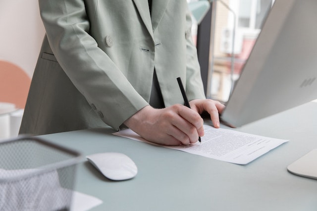 writing on a paper at a desk near a computer